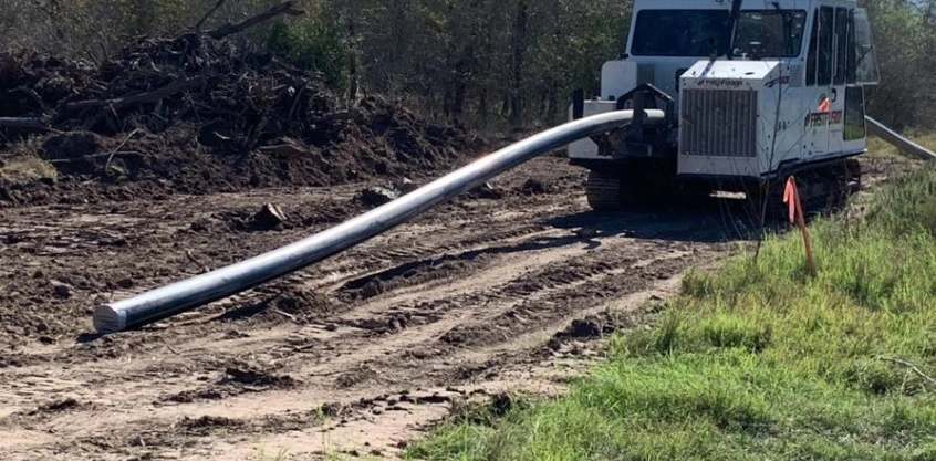 A large pipe being transported on a truck bed.