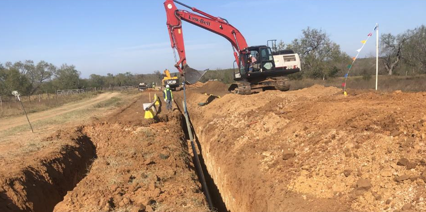 A Link-Belt 250 X4 EX excavator digging a trench in the dirt.