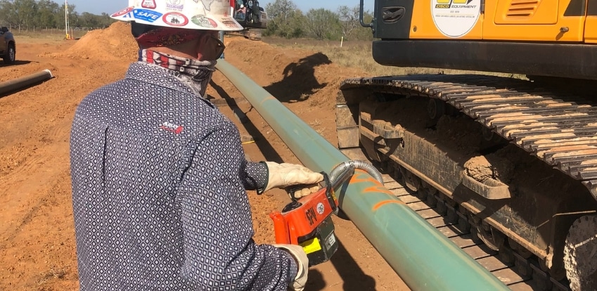 A man working on a pipeline site on a sunny day.